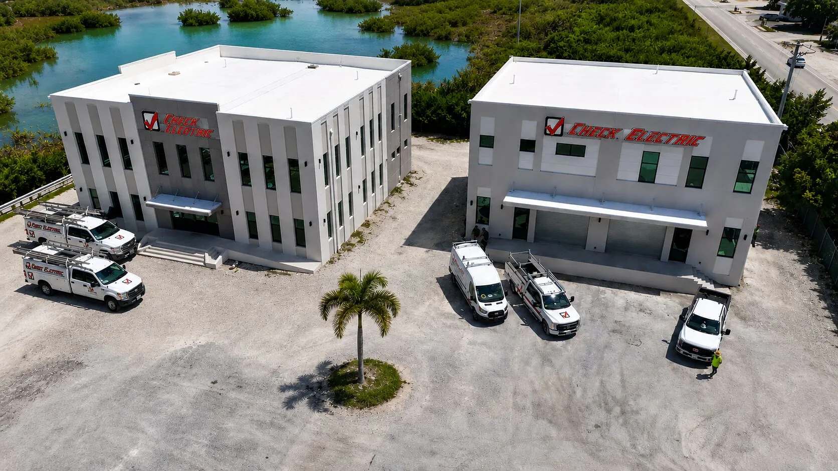 Aerial view of Check Electric's new Summerland Key campus, both the administrative building and the two-storey warehouse, with the fleet parked between them
